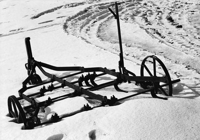361189 Afbeelding van een oud landbouwwerktuig in de sneeuw.